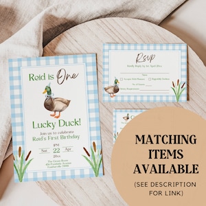 May include: A blue and white gingham patterned invitation for a first birthday party. The invitation features a cartoon duck wearing a party hat and the text "Reid is One" and "Lucky Duck!" The invitation also includes the text "Join us to celebrate Reid's First Birthday" and the date and time of the party.