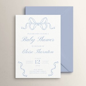 May include: A light blue baby shower invitation with a decorative bow at the top. The invitation reads "Please join us for a Baby Shower in honor of Eloise Thornton. March 12, 20XX. Bleu Boom, 221 Columbia Street, Boughville, CA 98765."