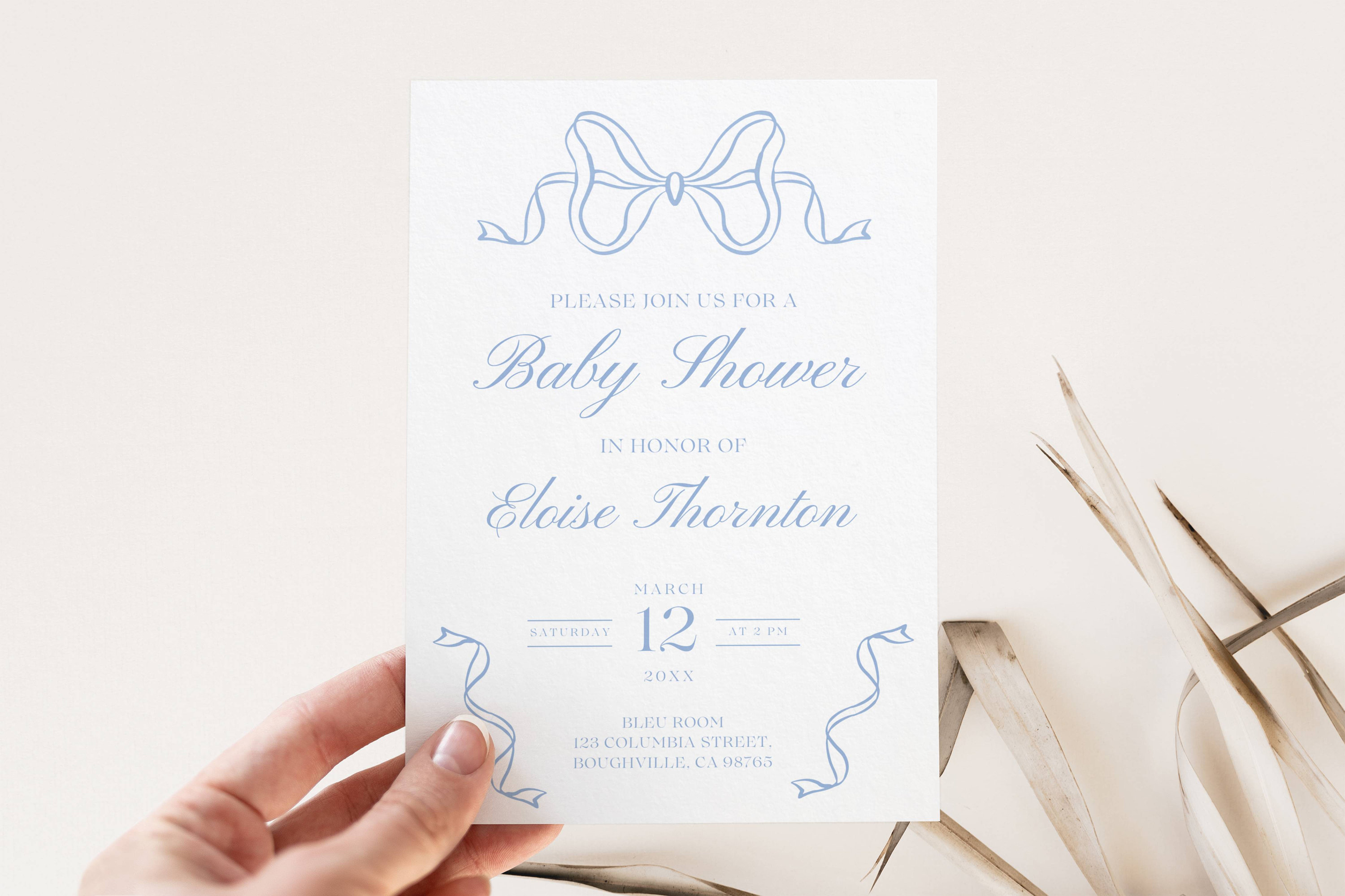 May include: A light blue baby shower invitation with a blue ribbon bow at the top. The invitation reads "Please join us for a Baby Shower in honor of Eloise Thornton. Saturday, March 12 at 2 PM. Blue Room, 123 Columbia Street, Boughville, CA 08765."