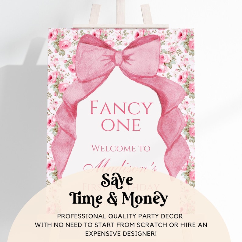 Op de afbeelding: Een roze en wit bedrukbaar bord met een grote roze strik en een bloemenpatroon. Het bord zegt "Fancy One" en "Welkom bij Madisons eerste verjaardag. Bespaar tijd en geld. Professionele partydecoratie van hoge kwaliteit, zonder dat je van scratch moet beginnen of een dure ontwerper hoeft in te huren!"