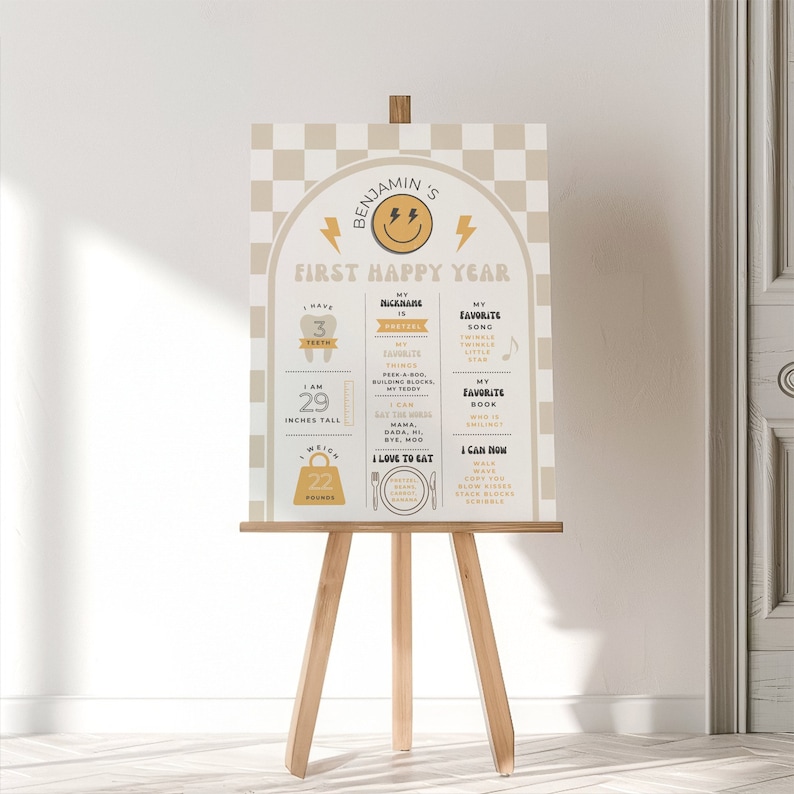 May include: A beige and yellow first birthday chart for a baby named Benjamin. The chart includes details about his first year, such as his height, weight, favorite song, and favorite book. The chart is decorated with a smiley face, a lightning bolt, and a checkered pattern.