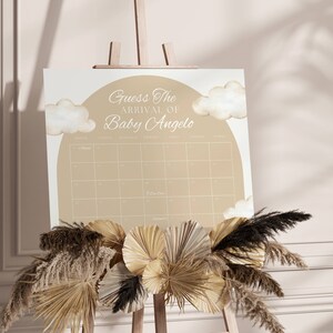 K&ouml;nnte beinhalten: Ein beige-wei&szlig;es Babyparty-Spielschild mit dem Text "Erraten Sie die Ankunft von Baby Angelo" und einem Kalenderrraster mit den Daten f&uuml;r den Monat November.