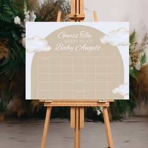 K&ouml;nnte beinhalten: Ein wei&szlig;es Schild mit einem braunen Kalender darauf. Das Schild lautet "Erraten Sie die Ankunft von Baby Angelo" und hat ein Aquarell-Wolken-Design.