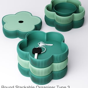 Puede incluir: Organizadores apilables con forma de flor en tonos verdes. Uno tiene tapa, otro un cuenco central y el tercero guarda llaves. Los organizadores son acanalados y apilables. El texto inferior dice "Round Stackable Organiser Type 3."