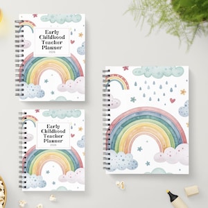 Op de afbeelding: Drie spiraalgebonden lerarenplanners met regenboog- en wolkenontwerpen. De covers tonen een aquarel regenboog, wolken, sterren en de tekst "Early Childhood Teacher Planner 2026". De planners liggen op een lichtgrijze ondergrond.