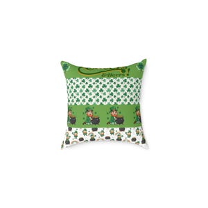 Op de afbeelding: Vierkantig decoratief kussen met een thema voor St. Patrick's Day. Het kussen heeft groen-witte strepen met klavers, kabouters, regenbogen en de tekst "& Beers!". Het kussen is vierkant en heeft een witte achtergrond.