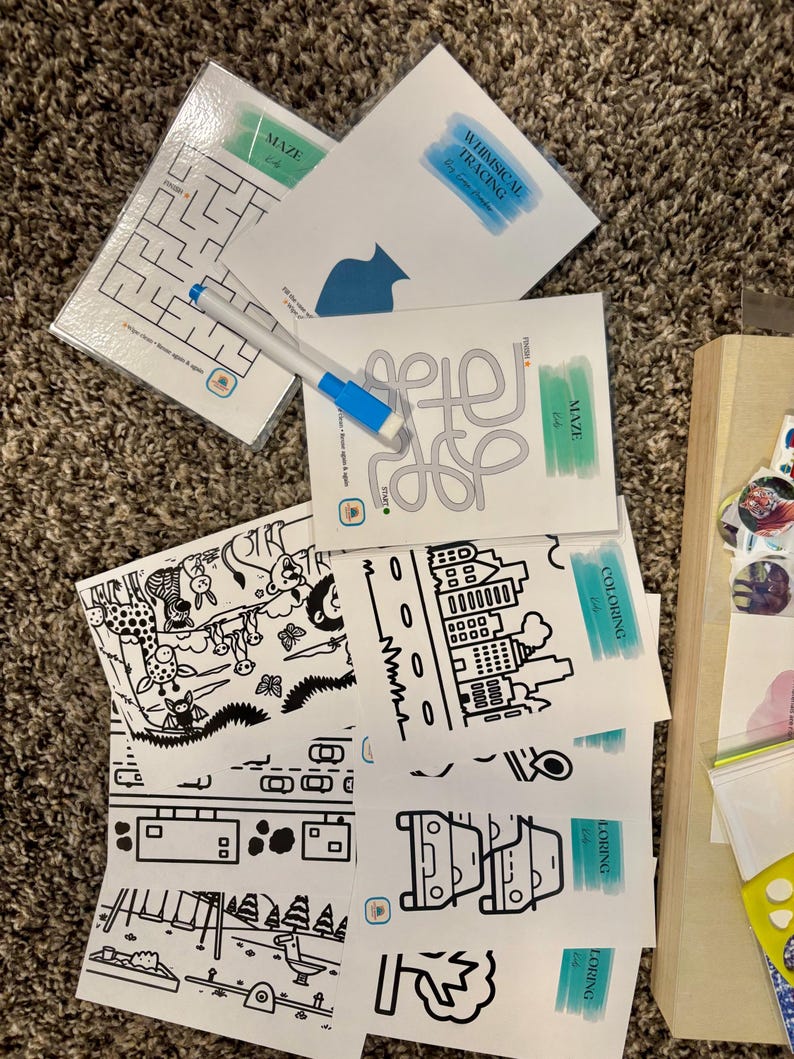 May include: A set of educational activity cards featuring mazes, tracing exercises, and coloring pages with black line art illustrations. The cards include text such as MAZE, WHIMSICAL TRACING, and COLORING, accompanied by a blue and white dry-erase marker.