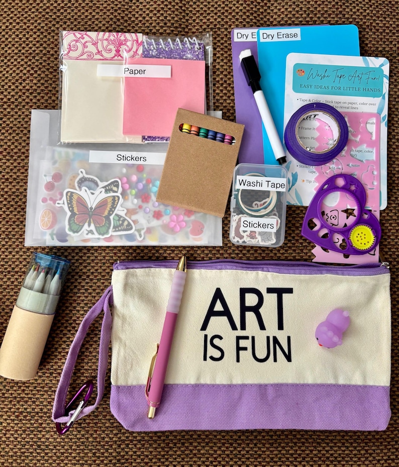 May include: A craft kit featuring a canvas pencil pouch with the text ART IS FUN, a dry erase board, a marker, washi tape, stickers, colored pencils, a stencil, and paper. The set includes various art supplies organized in clear plastic bags and boxes.