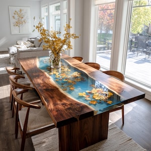 May include: A handcrafted wooden dining table with a unique epoxy resin river design. The table features a dark wood grain with a blue resin center filled with autumn leaves. The table is approximately 100 inches long.
