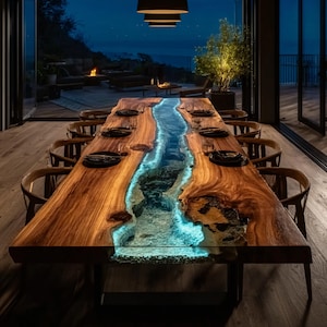 May include: A large, wooden dining table with a river-like design. The table features a live edge and a blue-lit resin center, resembling a flowing river. The table is surrounded by wooden chairs and set with plates.