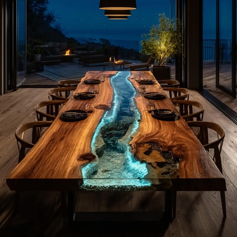 May include: A large, wooden dining table with a river-like design. The table features a live edge and a blue-lit resin center, resembling a flowing river. The table is surrounded by wooden chairs and set with plates.