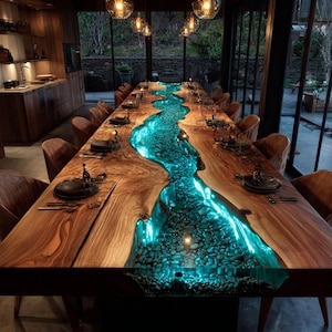 May include: A long, wooden dining table with a river-like design. The center of the table is filled with blue-lit resin and small stones, creating a unique visual effect. The table is surrounded by chairs and set with place settings.