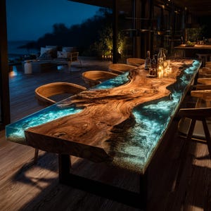 May include: A large, custom-made dining table with a live edge wooden top and a river of blue resin. The table is supported by a black metal base and surrounded by wooden chairs. The table is illuminated by candles and ambient lighting.