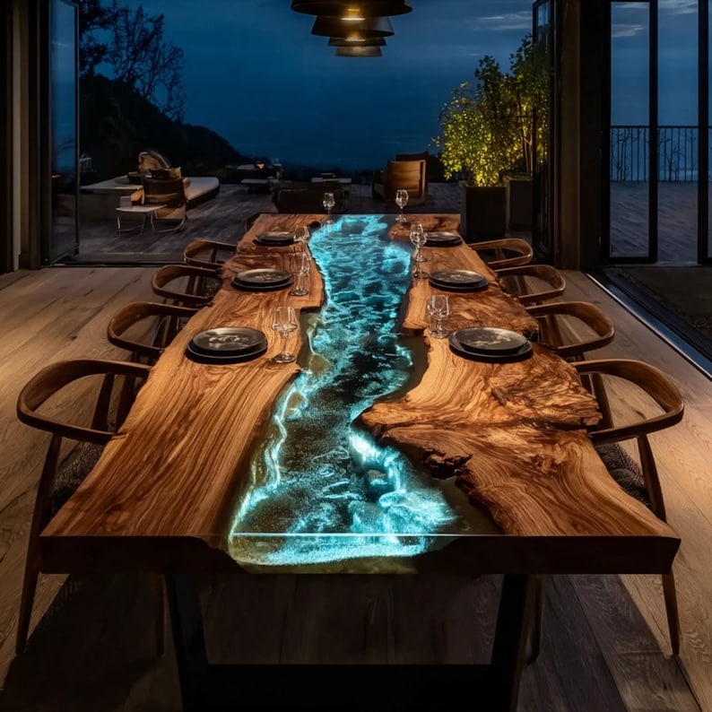 May include: A large, custom-made dining table with a unique design. The table features a live-edge wooden surface with a glowing, blue-lit river of resin running down the center. The table is set with plates, glasses, and chairs, creating an elegant dining experience.