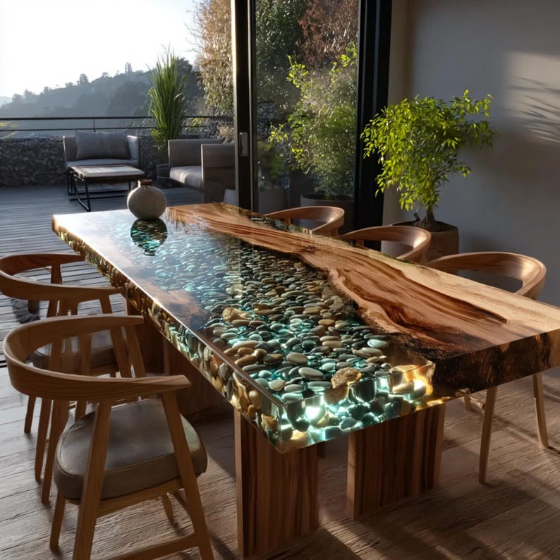 Pu&ograve; includere: Un tavolo da pranzo in legno fatto a mano con un fiume di resina trasparente con pietre incastonate. Il tavolo ha un bordo vivo ed &egrave; sostenuto da gambe in legno. Intorno al tavolo ci sono sedie in legno con cuscini di colore chiaro.