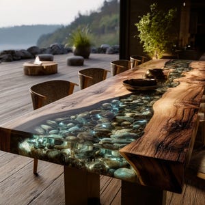 Pu&ograve; includere: Un tavolo da pranzo in legno su misura con un fiume di pietre incastonate in resina trasparente. Il tavolo ha un bordo in legno naturale ed &egrave; sostenuto da una base marrone scuro. Sedie in vimini circondano il tavolo. Il tavolo &egrave; lungo circa 200 cm.