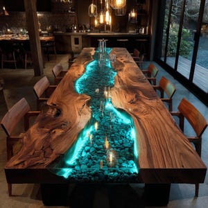 May include: A large, custom-made dining table with a unique design. The table features a river of blue-lit resin and stones running down the center, framed by live-edge wood. The table is surrounded by wooden chairs, creating a warm and inviting atmosphere.