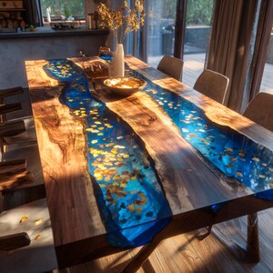 May include: A handcrafted wooden dining table with a unique river design. The table features a rich, dark wood grain with a vibrant blue epoxy resin river running through the center. The river is adorned with embedded golden-colored leaf accents. The table is surrounded by wooden chairs.