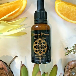 Puede incluir: Una botella de vidrio negro con un gotero que contiene un líquido transparente. La botella está etiquetada con "Hause of Venusia Pure Skin Elixir Goddess V Potent Vitamin C Anti-aging Face Serum".