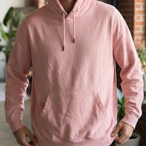 Puede incluir: Una sudadera con capucha rosa claro con capucha con cordón y bolsillo tipo canguro. La sudadera de manga larga está hecha de un material suave y tiene un ajuste relajado. La sudadera con capucha es de color sólido.