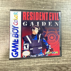 May include: A Game Boy Color video game cartridge for Resident Evil Gaiden. The cover art features a character in a police uniform with the text "Raccoon Police" and "Capcom". The game is rated "Teen".