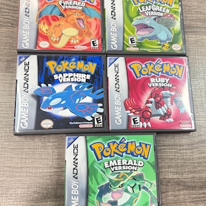 May include: A collection of six Game Boy Advance Pokémon video game cartridges. The game cases feature colorful artwork and titles such as "FireRed Version," "LeafGreen Version," "Sapphire Version," "Ruby Version," and "Emerald Version."