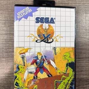 May include: A Sega X-Men video game cartridge box. The box features a grid pattern with the Sega logo and the text "Adventure Role-Playing." The bottom half depicts a warrior battling green creatures with swords.