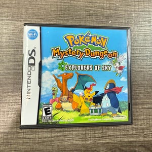May include: A Nintendo DS game case for "Pokémon Mystery Dungeon: Explorers of Sky." The cover features various Pokémon characters against a blue sky background. The game case has the Nintendo DS and Wi-Fi connection logos.