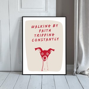 Puede incluir: Lámina artística enmarcada con una ilustración roja de un perro y el texto "WALKING BY FAITH TRIPPING CONSTANTLY". El perro tiene ojos y orejas grandes. El fondo es de color beige claro. El marco es negro.