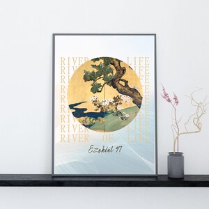 以下が含まれることがあります： 金色の円の中に木と川が描かれた額装アートプリント。 「RIVER OF LIFE」の文字が縦に印刷されています。テキスト「Ezekiel 47」は下部にあります。 黒い棚に飾られたアートワークです。