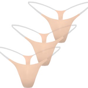May include: Three pairs of nude-colored thong underwear with white straps. The underwear is made of a soft, seamless material. The thongs are arranged in a diagonal pattern against a white background.