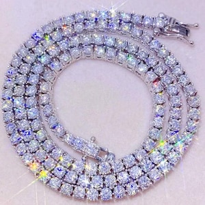 May include: A white ceramic mug with a black handle and the text "But First, Coffee" in a black, handwritten-style font. The mug is on a white surface.