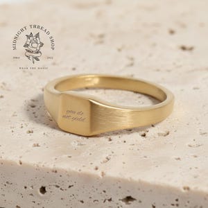 Könnte beinhalten: Ein goldfarbener Siegelring mit rechteckiger Oberfläche, graviert mit den Worten "you do not yield". Der Ring liegt auf einer strukturierten, hellen Oberfläche. Das Logo von Midnight Thread Shop ist im Hintergrund zu sehen.