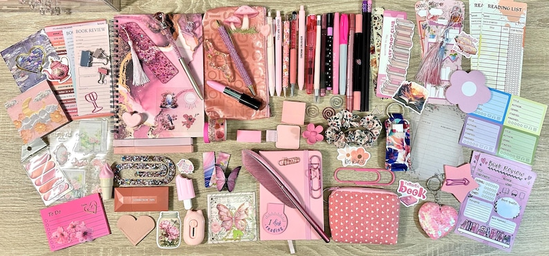 Pu&ograve; includere: Una collezione di articoli di cancelleria nei toni del rosa che include un quaderno a spirale, una penna a piuma, varie penne gel, pennarelli, foglietti adesivi, graffette, un piccolo astuccio a pois, adesivi decorativi e schede di lettura.