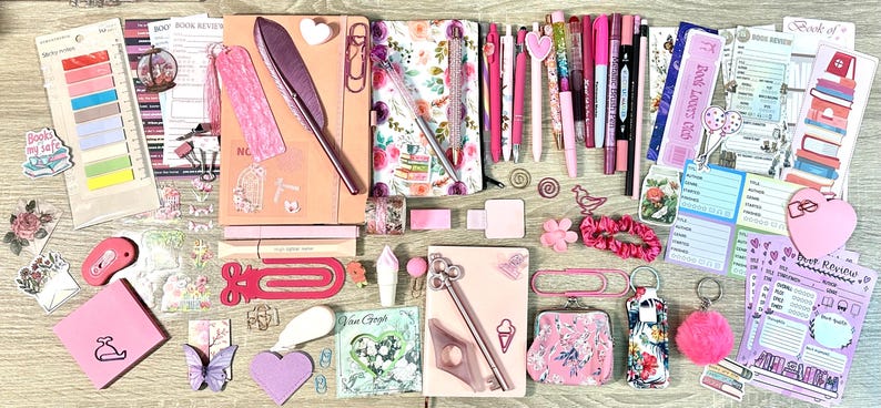 Pu&ograve; includere: Una collezione di articoli di cancelleria rosa e floreali che include quaderni, penne, segnalibri, foglietti adesivi, graffette e schede per recensioni di libri. L'assortimento presenta varie tonalit&agrave; di rosa, motivi floreali e piccoli elementi decorativi.