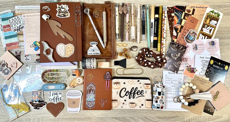 May include: A collection of stationery items including two brown notebooks, a pencil case with the word Coffee, various pens, markers, stickers, bookmarks, paper clips, a scrunchie, and book review cards, all featuring coffee and reading-themed designs.
