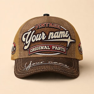 May include: A brown and tan baseball cap with the words "Vintage Your name Original Parts" embroidered on the front. The brim of the cap is a darker brown, and the cap has a curved peak.