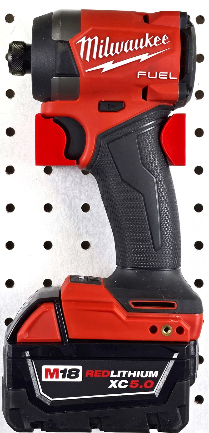 May include: A red and black Milwaukee FUEL impact driver with a black battery pack. The tool is mounted on a white pegboard with red brackets. The Milwaukee logo is prominently displayed.