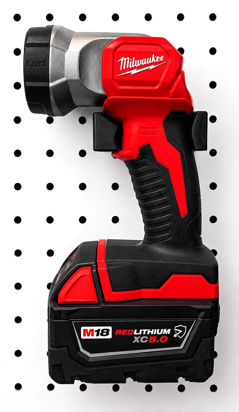 May include: A red and black Milwaukee M18 LED work light and battery pack. The work light has a silver head and the Milwaukee logo. The battery pack is labeled M18 RedLithium XC5.0. The work light is mounted on a white pegboard.