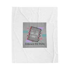 Peut inclure: Couverture blanche avec un motif carré gris. Le motif présente un effet de glitch avec des accents rouges, turquoise et violets. Le texte "Embrace the Static" est en bas du motif.