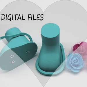 May include: Two teal blue 3D printed baby shoes with a strap on one shoe. The shoes are on a white surface with pink, blue, and purple artificial flowers.