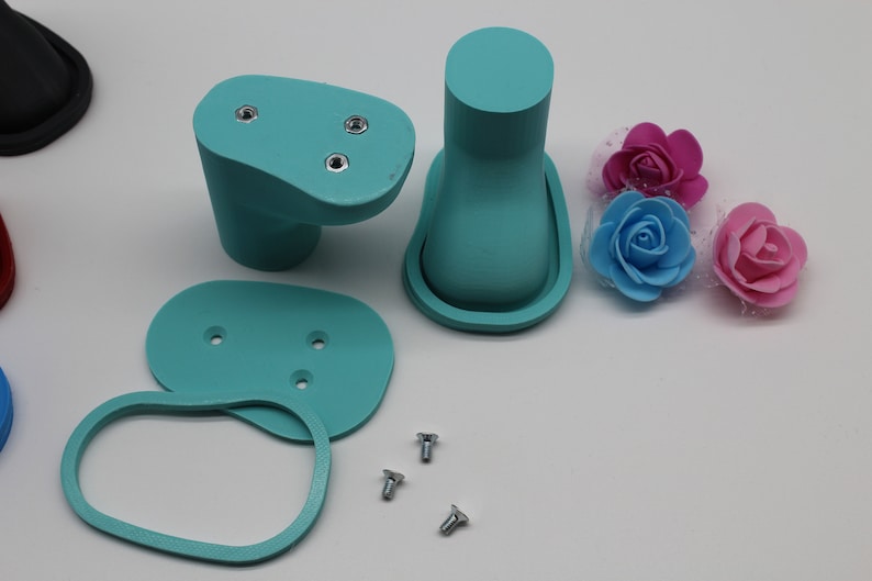 May include: A set of teal blue plastic parts for a 3D printed model, including two oval-shaped pieces with screw holes, a tall cylinder with a rounded top, and a smaller oval-shaped piece. There are also three silver screws.