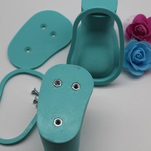 May include: A set of turquoise blue 3D printed shoe molds with screw holes. The molds are for making shoes and are shown on a white surface.