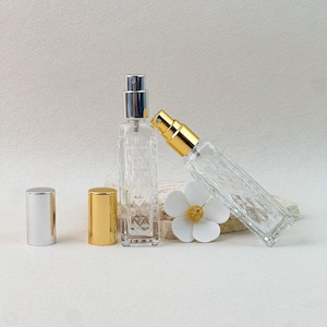 Silver and gold cap perfume atomizer bottles standing upright and tilted, with extra caps and flower decor.