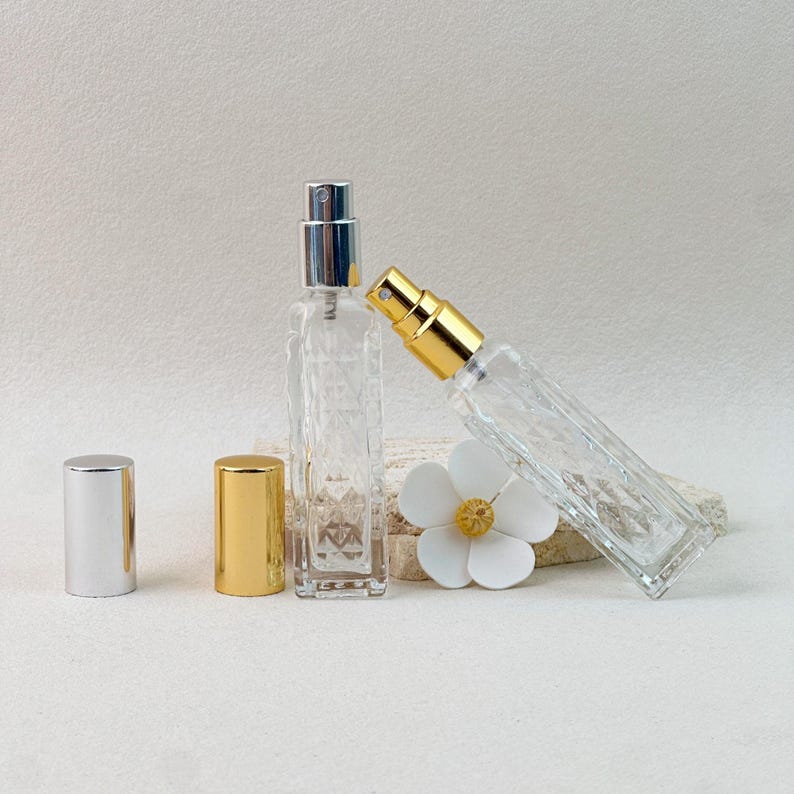 Silver and gold cap perfume atomizer bottles standing upright and tilted, with extra caps and flower decor.