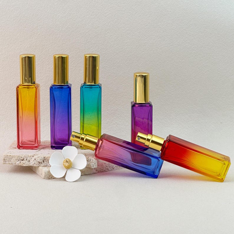 Multiple gradient perfume bottles arranged with natural props, highlighting the vibrant rainbow colors and gold caps.