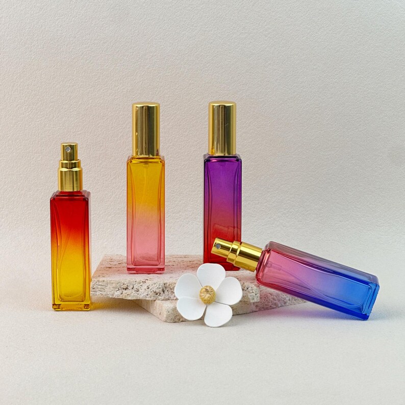Red-Yellow, Pink-Blue, and Teal-Yellow gradient perfume bottles, some open to show the spray pump and cap.
