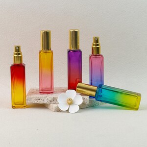 All six gradient perfume bottles displayed together, styled with natural decor to highlight the full range of color options.