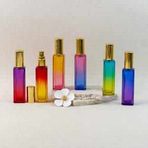 All six gradient perfume bottles displayed at different angles, with one bottle open to show the gold spray pump mechanism and cap removed.