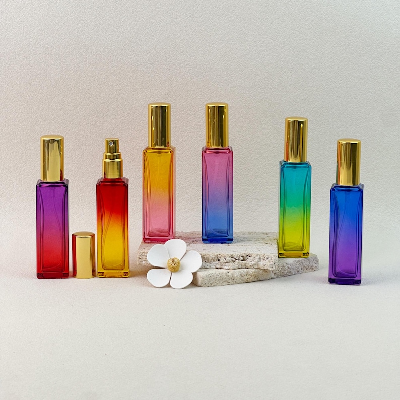 All six gradient perfume bottles displayed at different angles, with one bottle open to show the gold spray pump mechanism and cap removed.